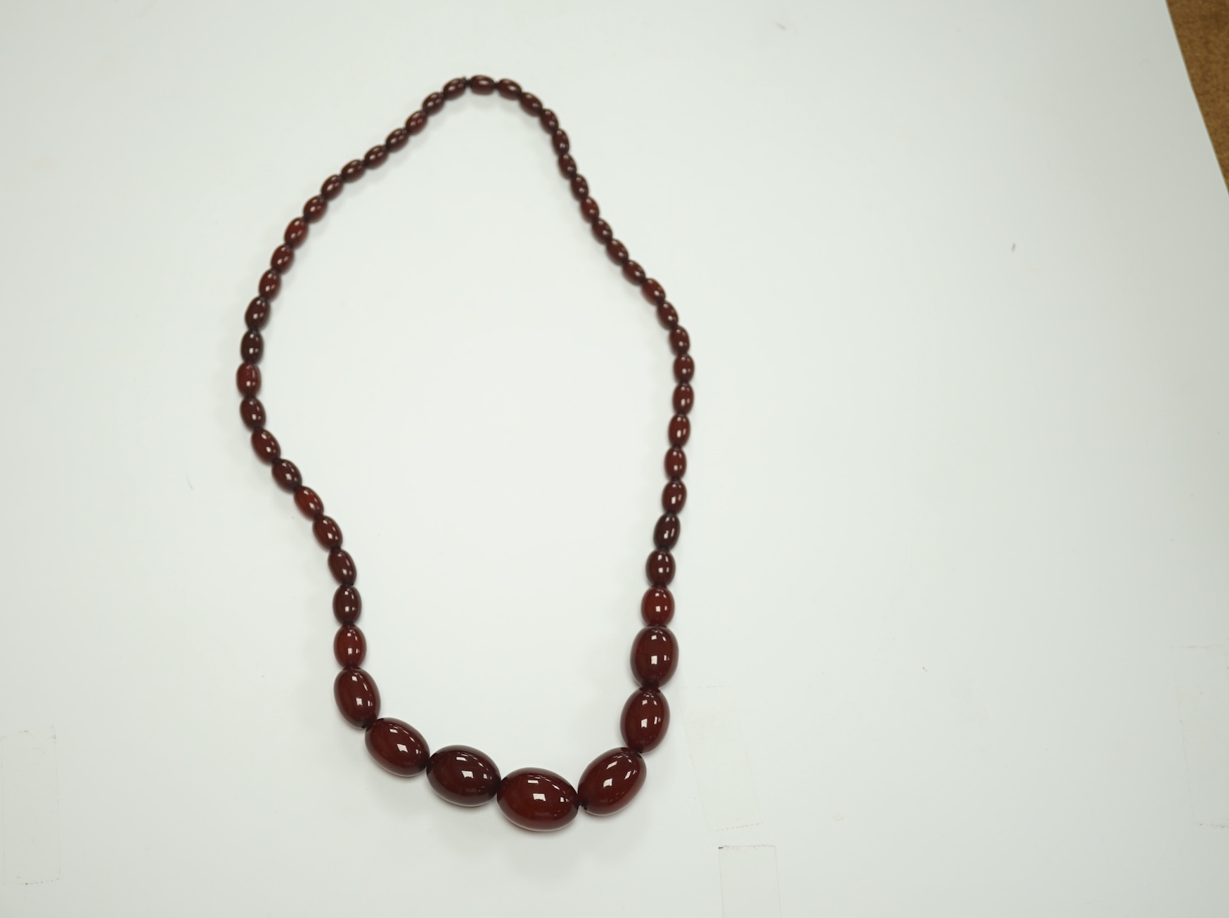 A single strand graduated oval simulated cherry amber bead necklace, 74cm, gross weight 71 grams. Condition - fair